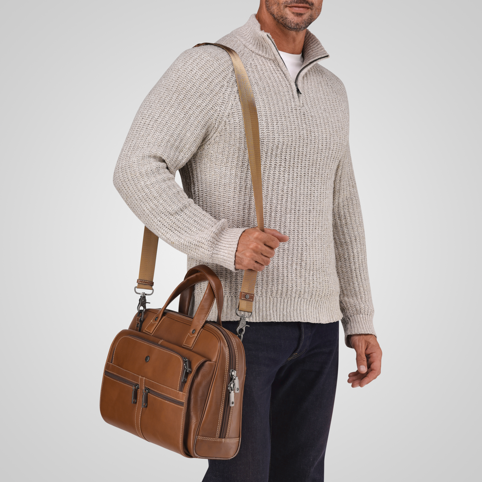 Man holding a brown leather bag against a light gray background