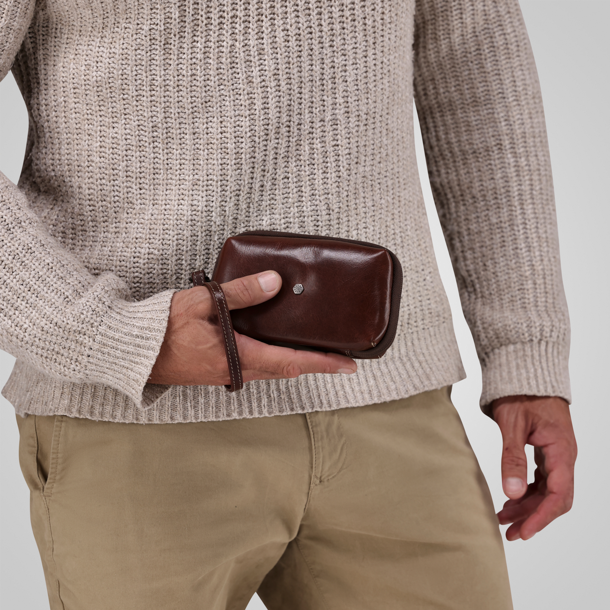 Person holding a brown leather wallet against a neutral background