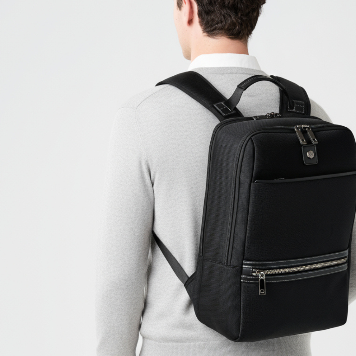 Person wearing a black backpack on a plain background