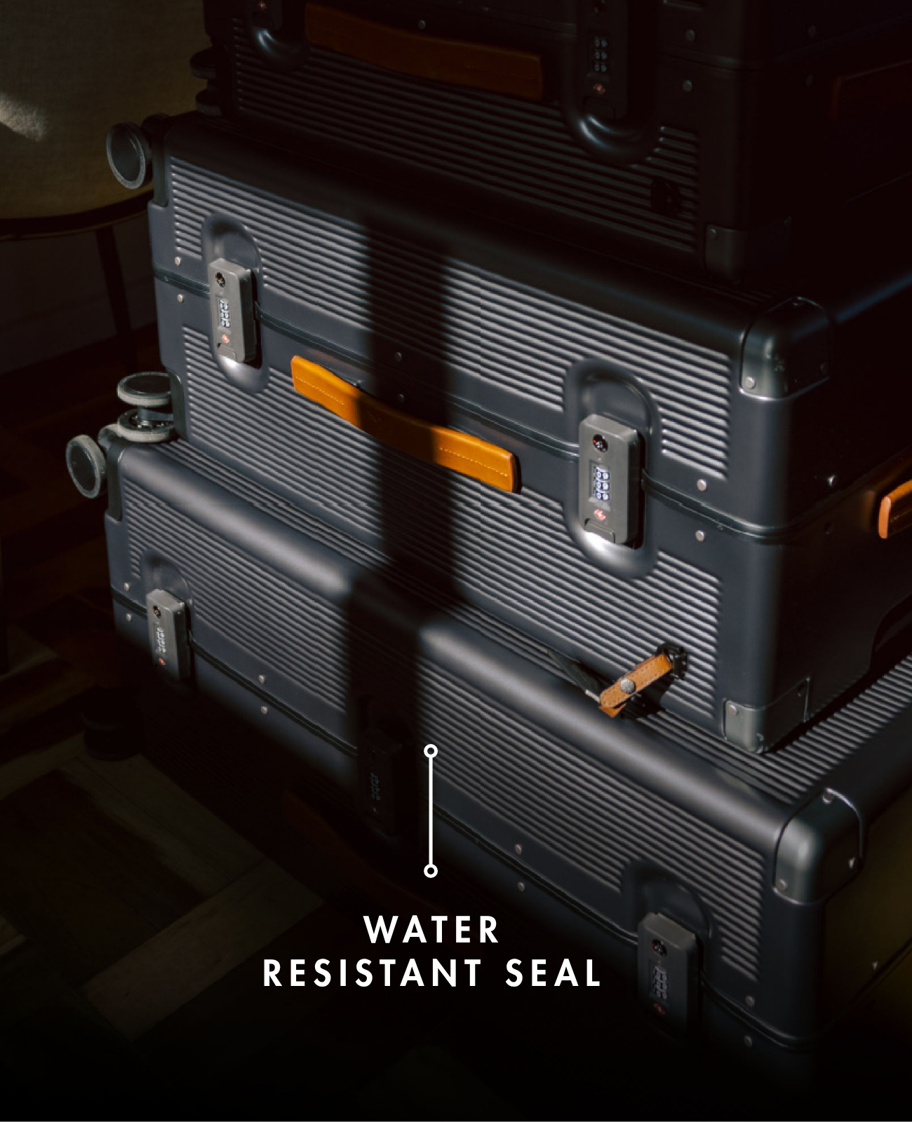 Stack of gray suitcases with water resistant seal feature on a dark background