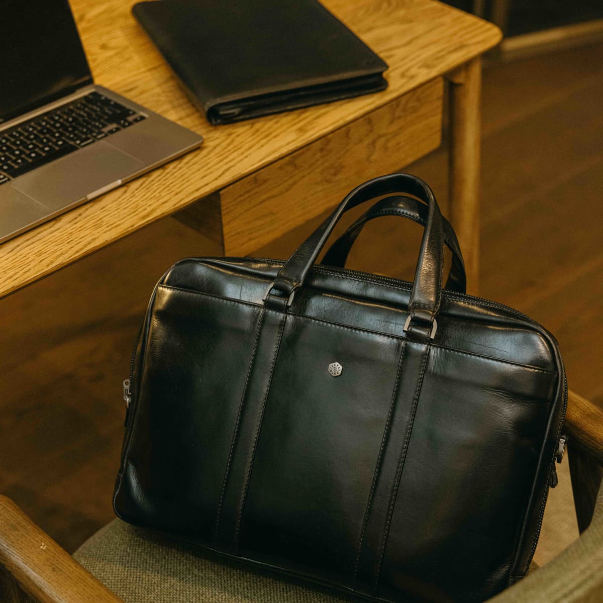Jekyll and Hide black leather 17 inch laptop briefcase on a desk next to a laptop