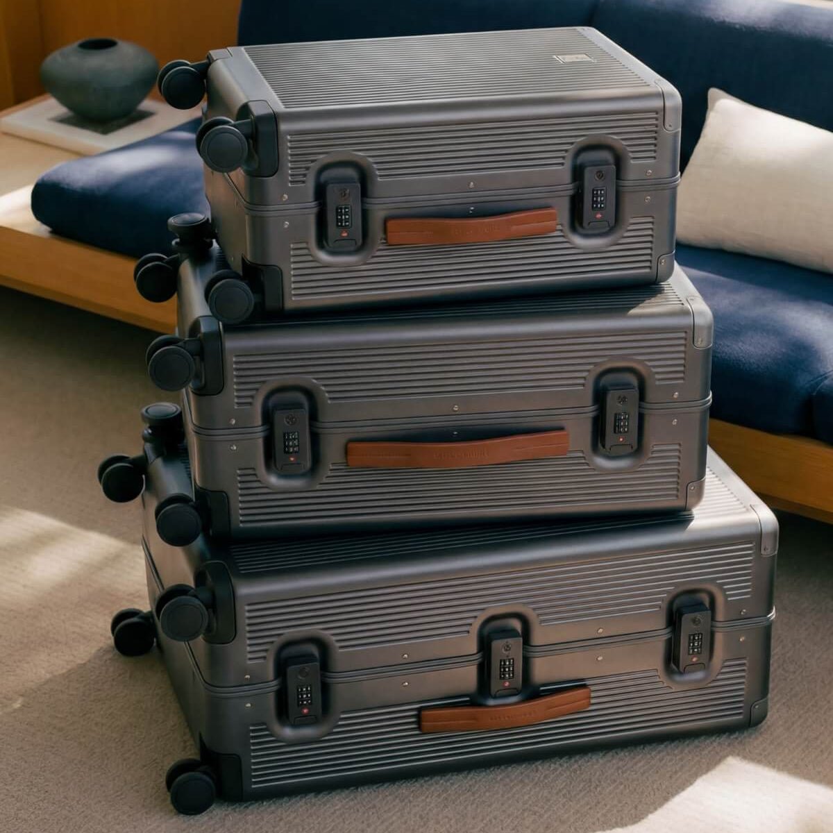 Stack of gray suitcases with brown handles on a light-colored floor.