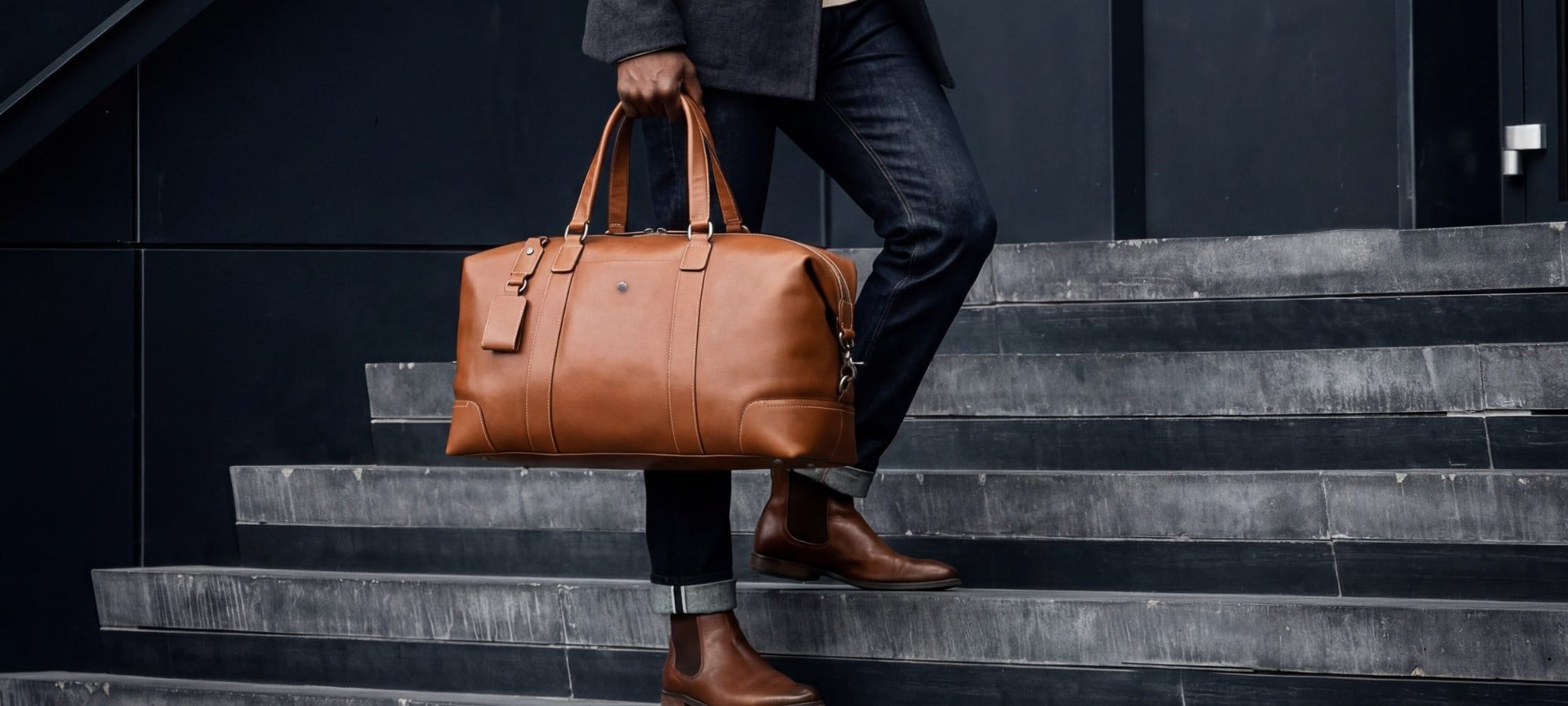 Person holding a brown leather briefcase on a staircase