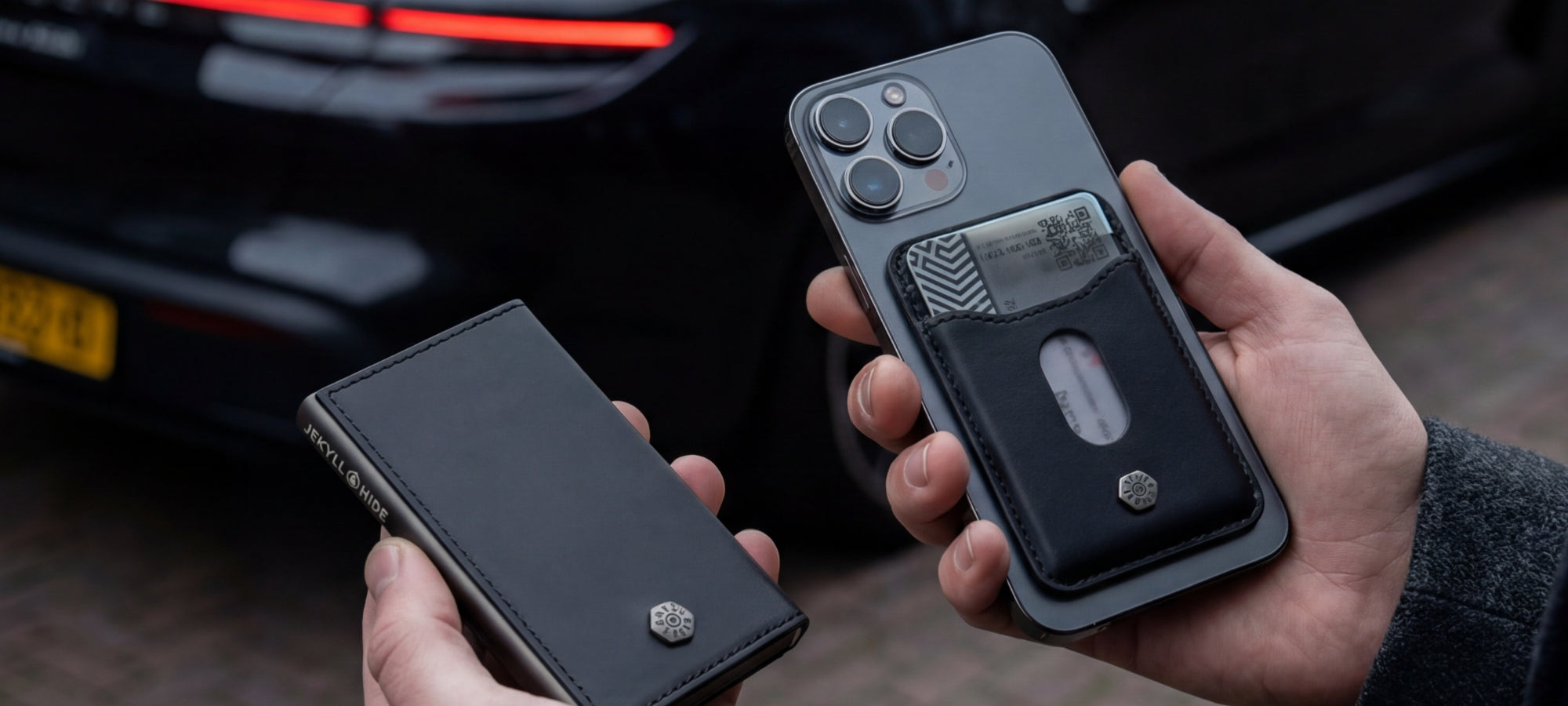Two phone cases being held in front of a car