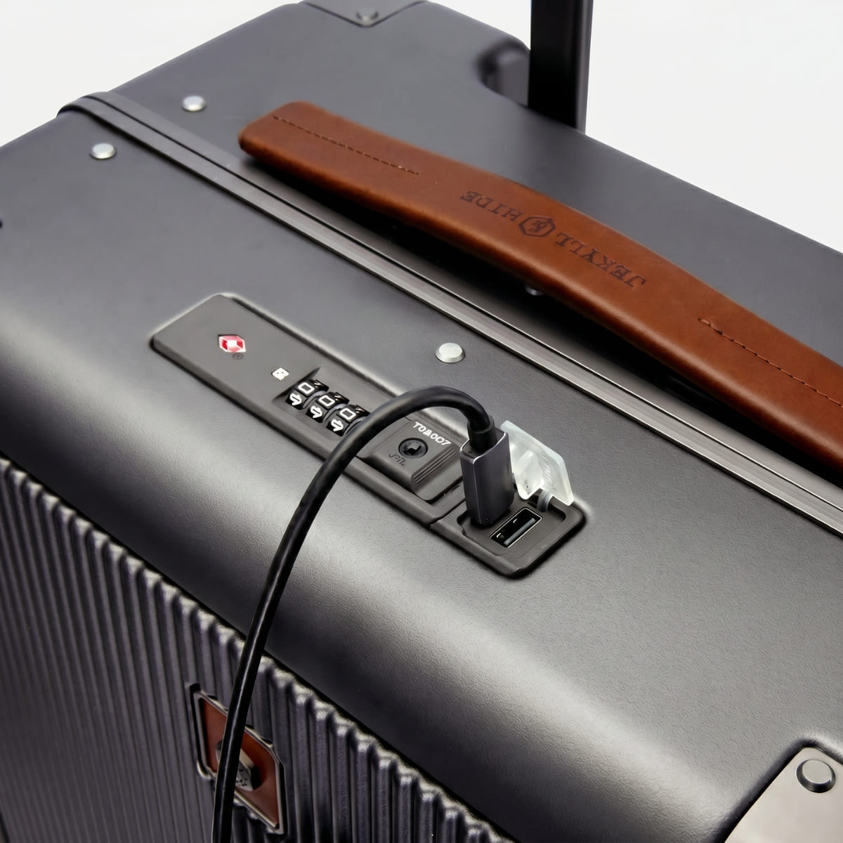 Close-up of a suitcase with power adapter and cable, featuring a brand logo.
