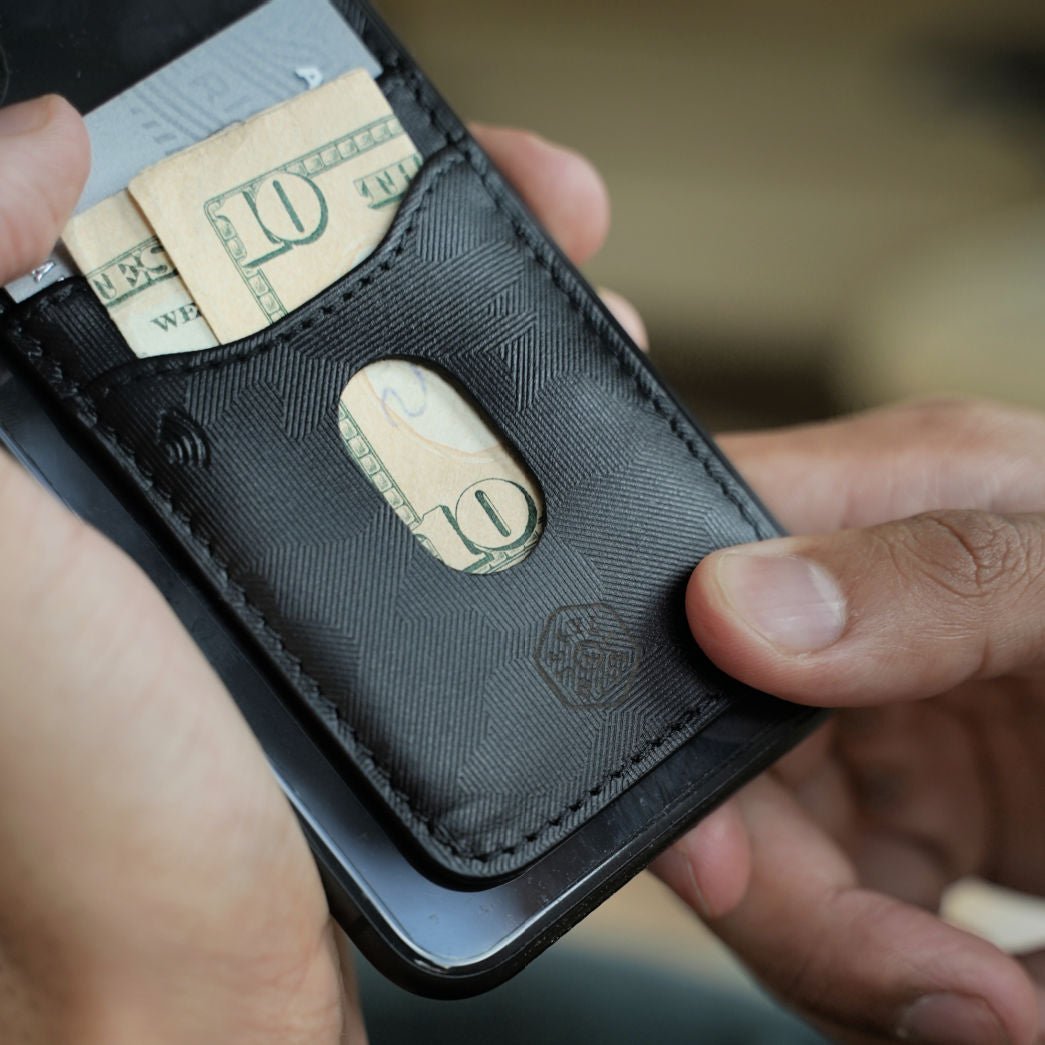 Man holding a phone with a Jekyll and Hide black camo leather stick-on card holder and cash