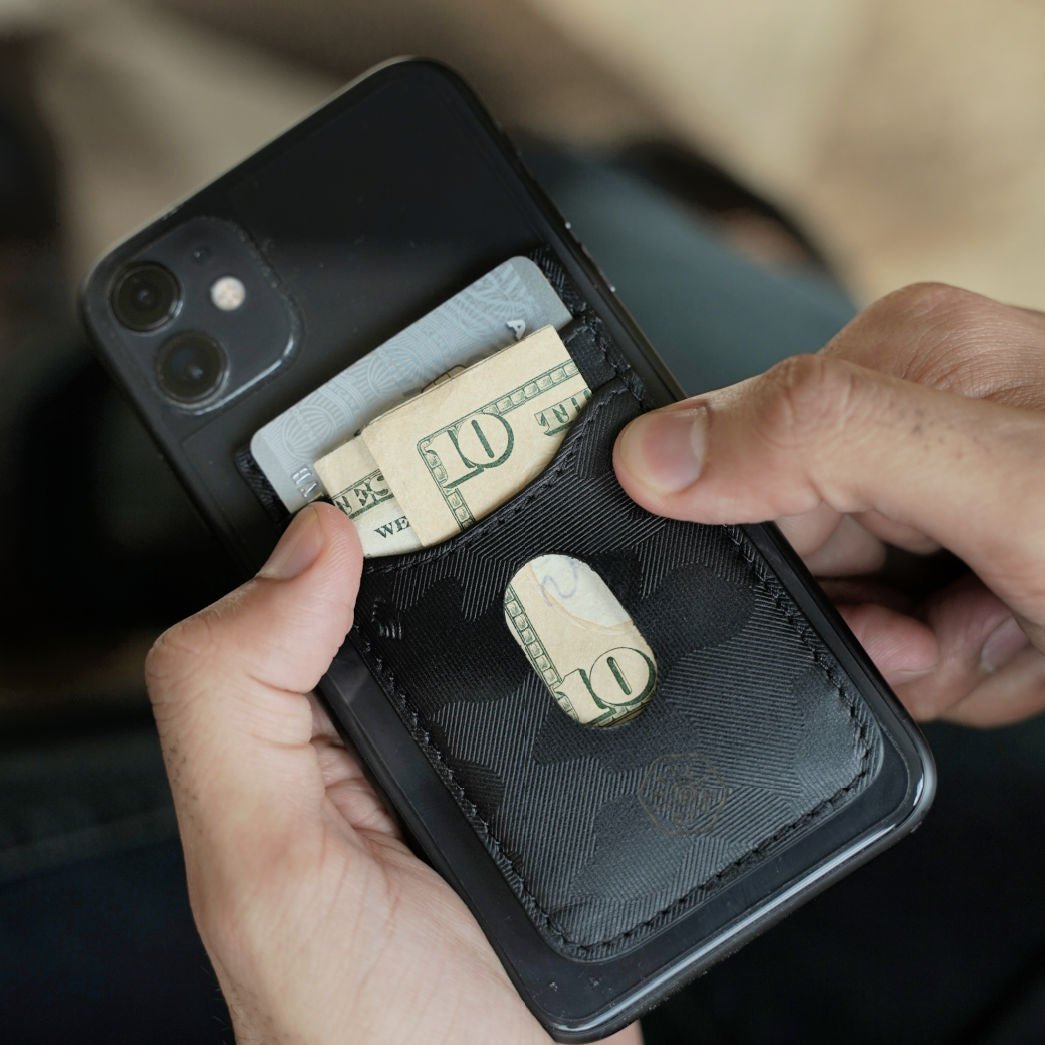 Man holding a phone with a Jekyll and Hide black camo leather stick-on card holder